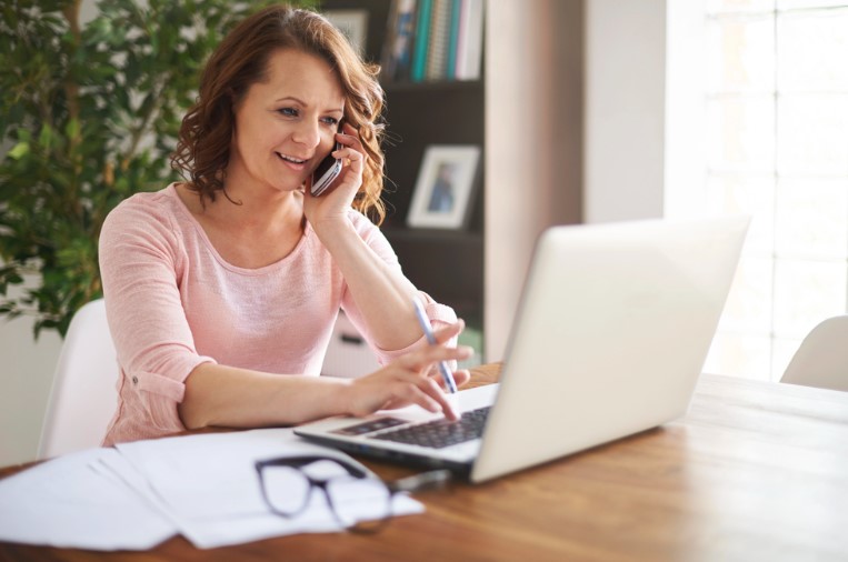 Eine Frau sitzt am Laptop und telefoniert